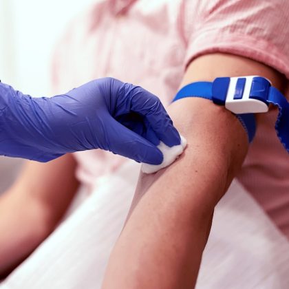 image shows a person getting a blood test with a glove and cotton pad