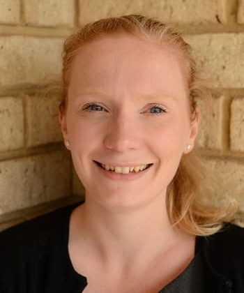 Dr Jacqui Sutton smiles at the camera. Her hair is long and in a ponytail