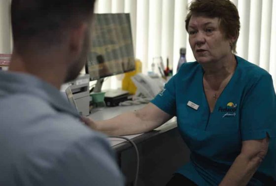 female doctor speaking to a man in front of a desk with a computer